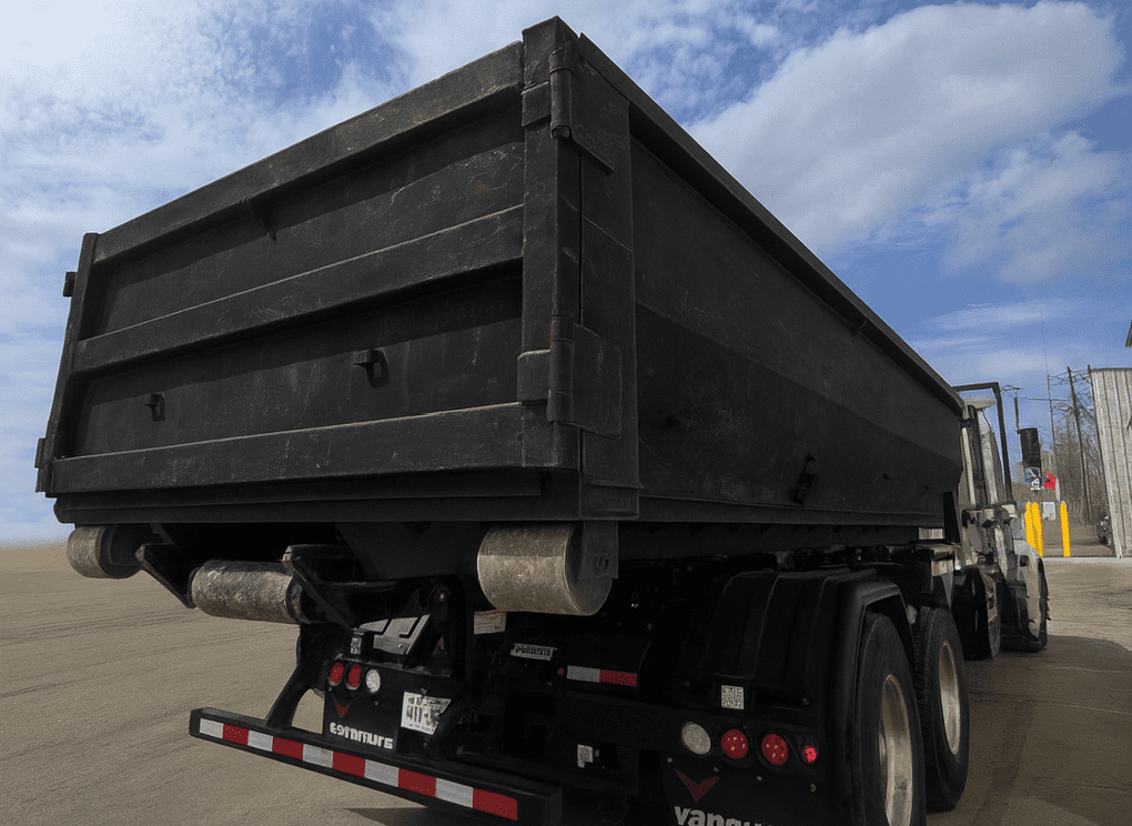 Black dump truck bed against a cloudy sky.