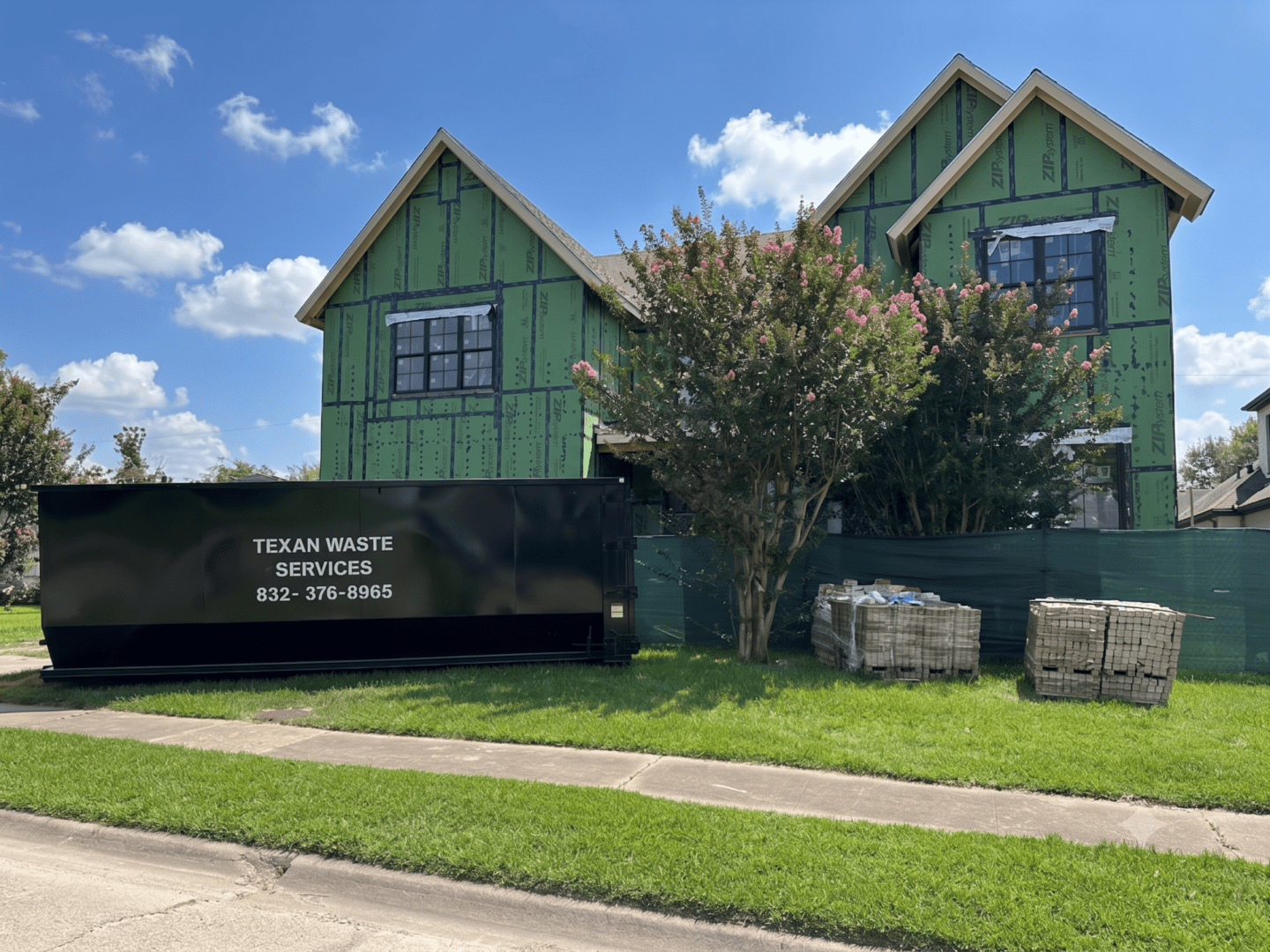 House under construction with dumpster and tree