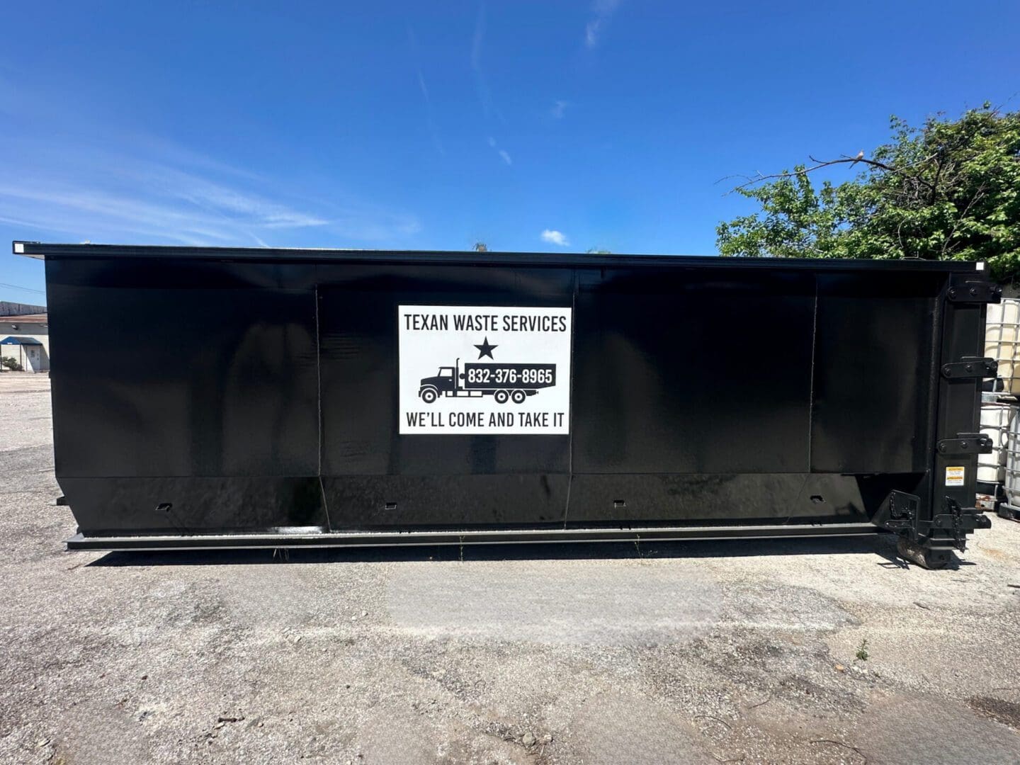 Large black waste dumpster with company sign