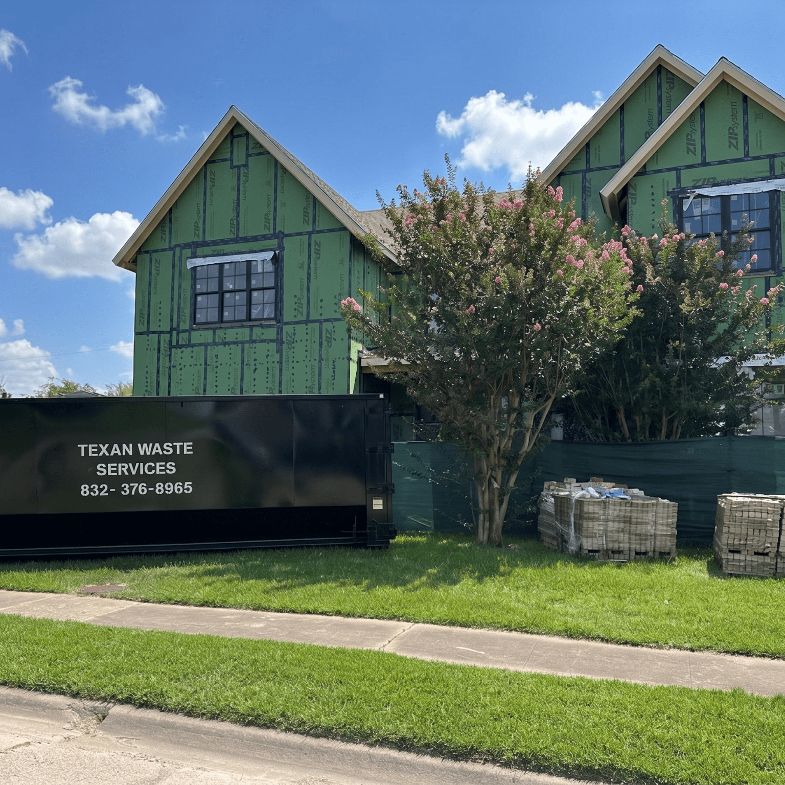 Two-story house under construction with dumpster